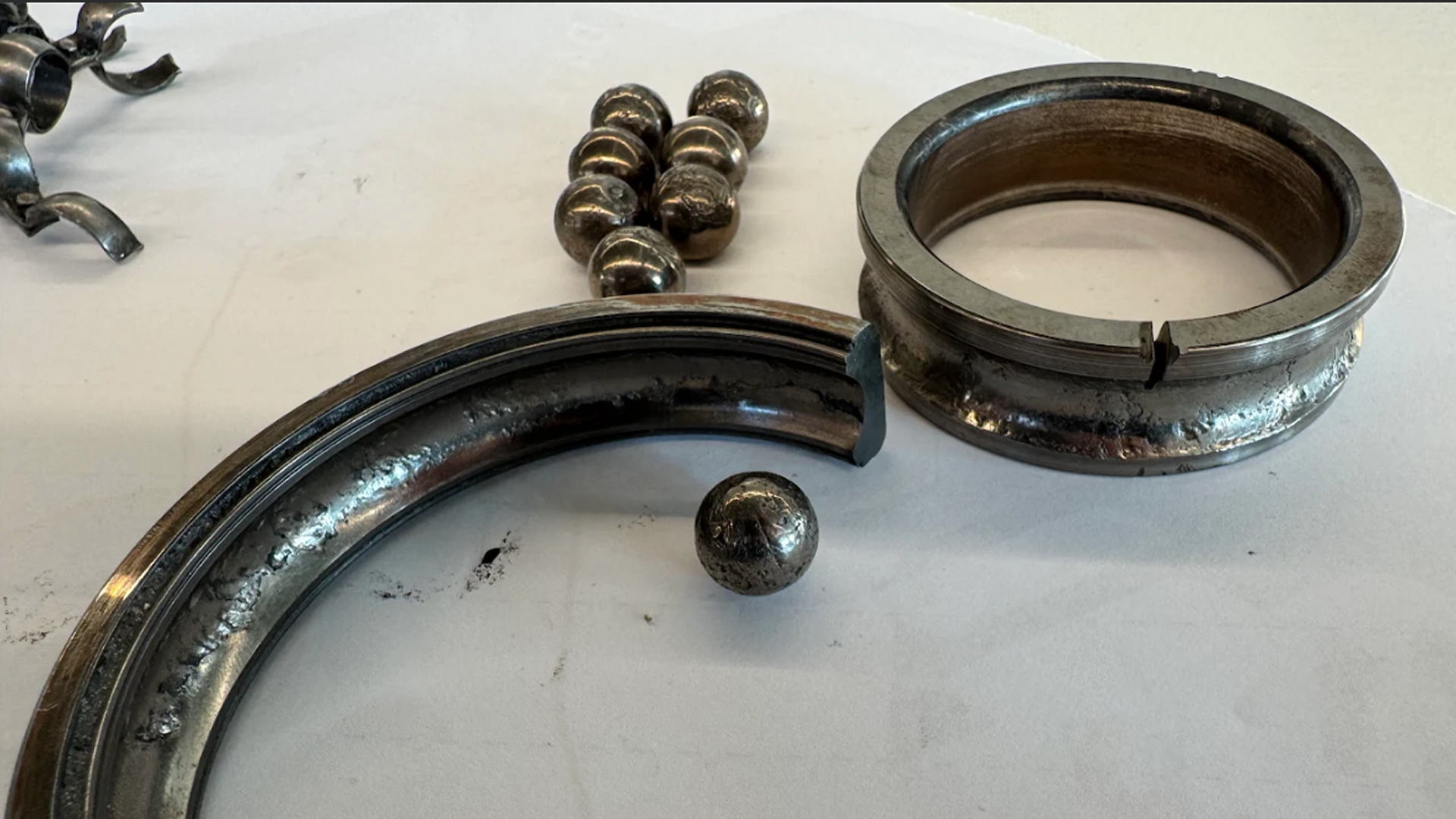 Severely damaged rolling element bearing with cracked raceways and worn balls showing advanced mechanical failure